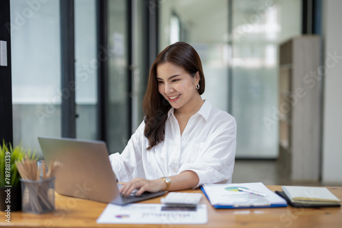 Joyful businesswoman with a victorious gesture, celebrating success while working on her laptop in a sunny office space.