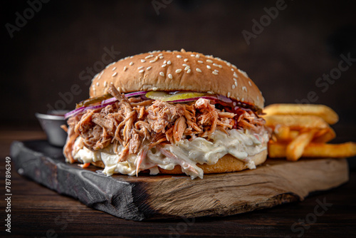 Burger with meaty beef fibers, mushroom sauce, cheese, veggies and roasted potatoes. Juicy delicious hamburger on darkmood picture for restaurant decoration, poster. 