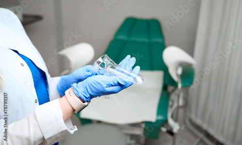 Pretty female doctor gynecologist in blue medical sterile gloves holding vaginal speculum. Women's health. Prevention illness. Early detection of cancer. Close up
