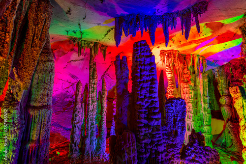 Inside the cave. Stalactites, stalagmites, colored light. Beautiful background