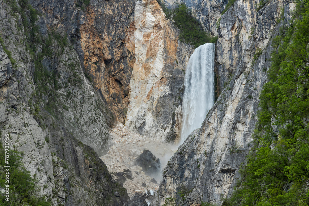 Boka waterfall in Slovenia, near Bovec. Easy trekking nature trail in the forest with the view of the immense waterfall overhanging the mountains visible from the road, long exposure photography.