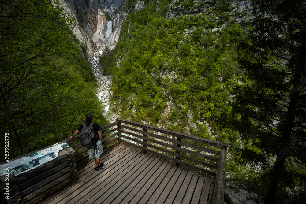 Boka waterfall in Slovenia, near Bovec. Easy trekking nature trail in the forest with the view of the immense waterfall overhanging the mountains visible from the road, long exposure photography.