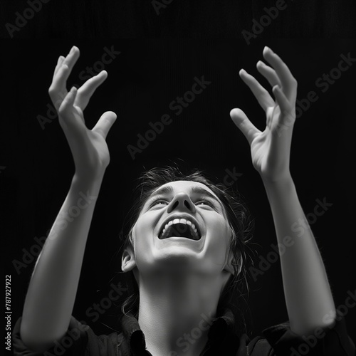 Joyful young woman with arms raised, looking upwards in a moment of happiness.