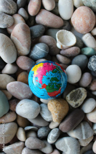 Top view of the North Pole on a miniature Earth globe on smooth rocks. Vertical stock photo for travel backgrounds