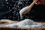 Wooden spoon pouring sugar or salt onto wooden surface with black background Ample space for text