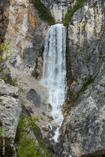 Boka waterfall in Slovenia  near Bovec. Easy trekking nature trail in the forest with the view of the immense waterfall overhanging the mountains visible from the road  long exposure photography.