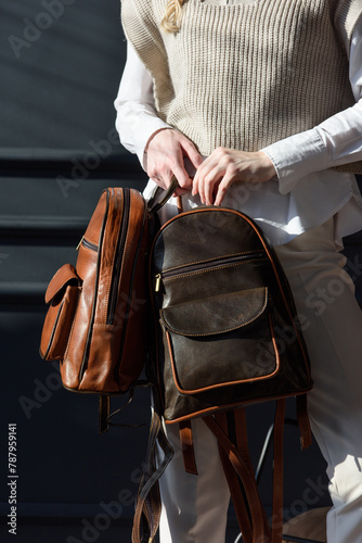 beautiful curly blond hair woman posing with a two leather backpacks