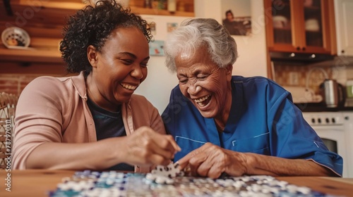 A cheerful woman helping an elderly lady with a puzzle at their residence. photo