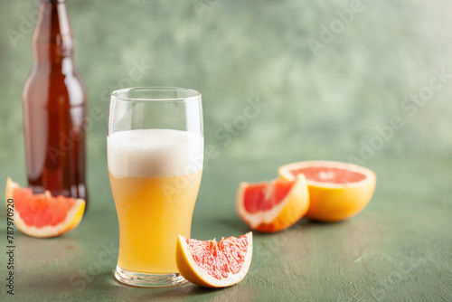 Boozy Refresing Cold Grapefruit Beer in a Pint Glass and Bottle on table. Copy space photo