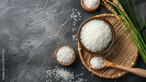 White rice (Thai Jasmine rice) in ceramic bowl and wooden spoon with ear of paddy on threshing basket,