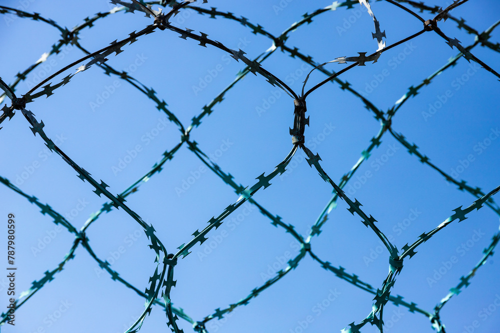 Stone wall with barbed wire against blue sky Stone wall with barbed wire against blue sky