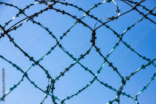 Stone wall with barbed wire against blue sky