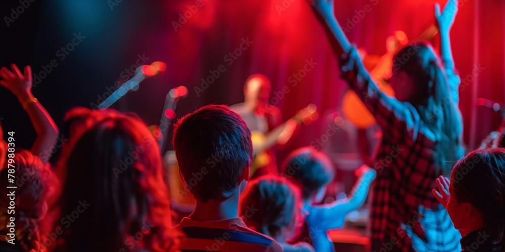 Captured in a concert hall, this image showcases a crowd enjoying a live performance, highlighted by the colorful lights creating a vivid background