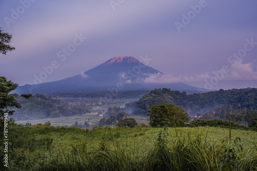 Stunning Sunrise Over Volcanic Mountain (mount Agung) and Lush Forest in early morning blue hour (purple sky)