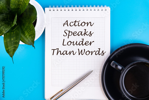Business term, phrase in a notebook with a cup of coffee and a pen on a blue background - actions speak louder than words