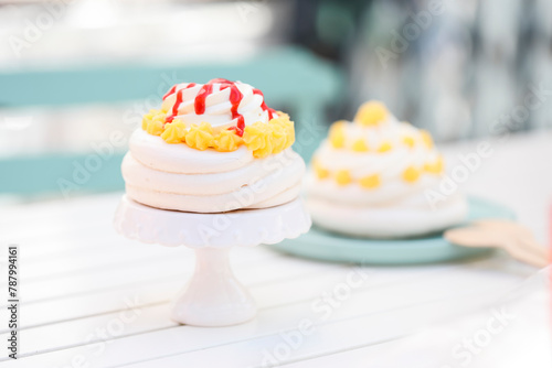 Pavlova with whipped cream and lemon curd  and a pavlova with strawberry coulis on a garden table photo