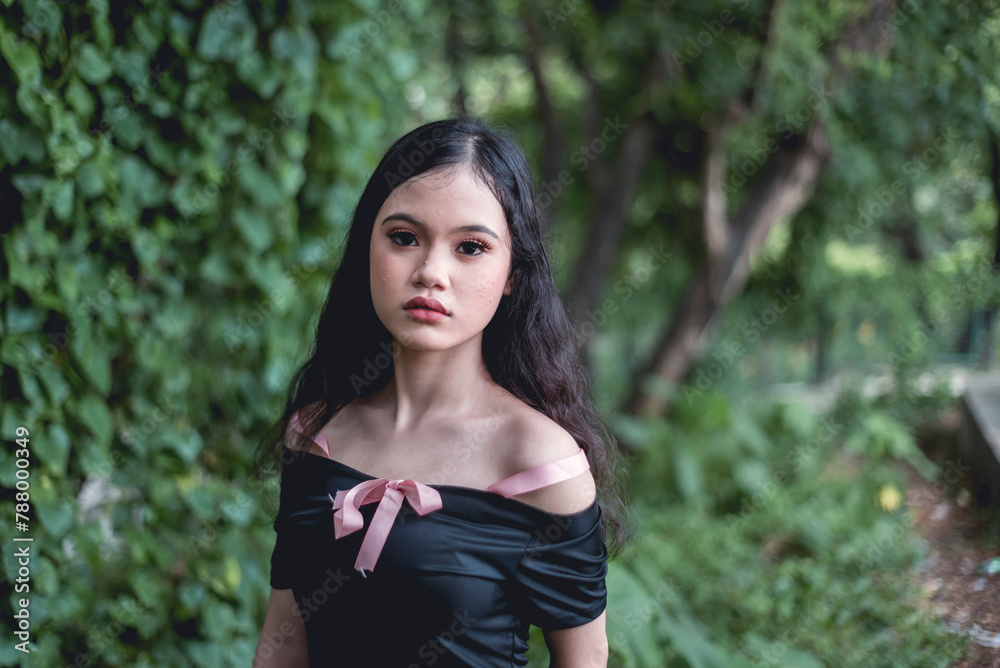 Fototapeta premium Young woman in goth-style dress posing in lush forest, capturing mystical and enchanting vibes