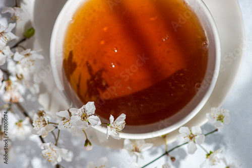 Overhead view of a cup of tea with cherry blossom stems in full bloom on a table photo
