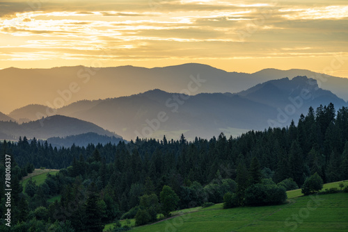 Idyllic landscape in the Pieniny Mountains with trees and fresh green meadows and foggy hills in the background photo