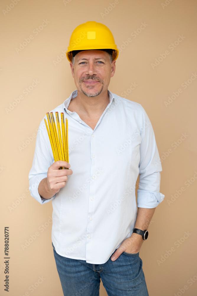 man, architect, technician, builder, polisher with yellow safety helmet and yellow folding rule against a brown background man, architect, technician, builder, polisher with yellow safety helmet and yellow folding rule against a brown background