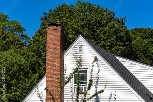 Home facade with white siding and brick chimney in Brighton, Massachusetts, USA