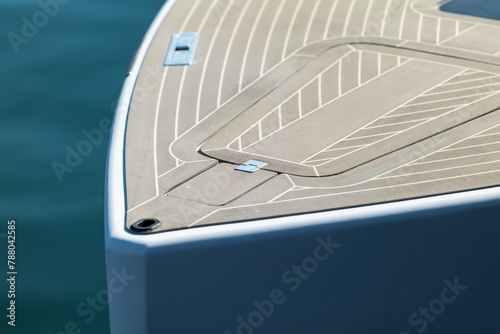 The bow of a beautiful powerboat with nice clean lines showing the deck and hatch.