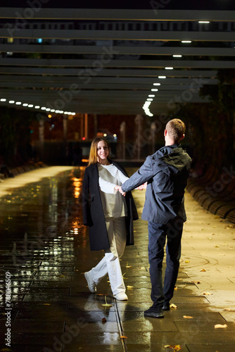 A beautiful young couple. A girl in white clothes and a man in black clothes at night in the park.