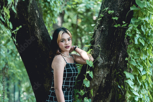 Young woman in goth-inspired attire posing thoughtfully in a lush forest