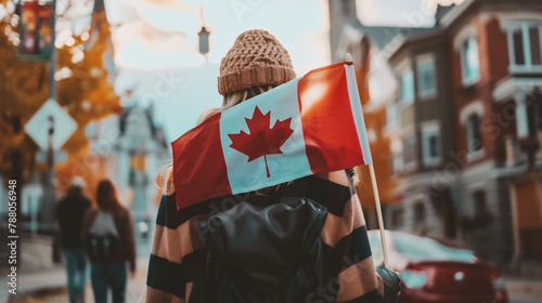 Young woman holding a canadian flag in her hands on the background of the city