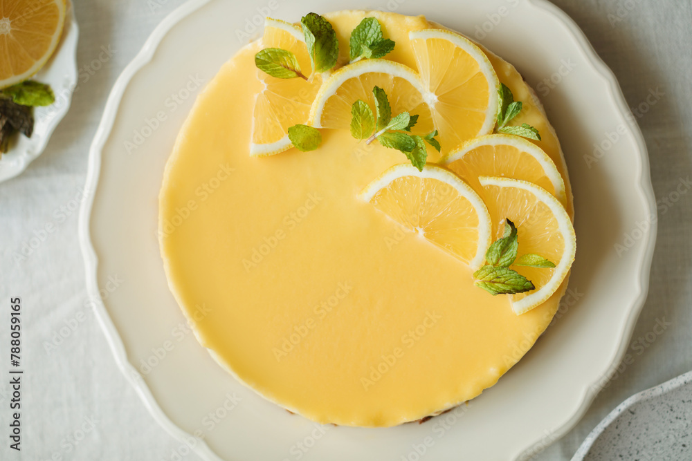 Overhead view of a Homemade low carb Lemon Cheesecake with fresh lemon and mint garnish Overhead view of a Homemade low carb Lemon Cheesecake with fresh lemon and mint garnish