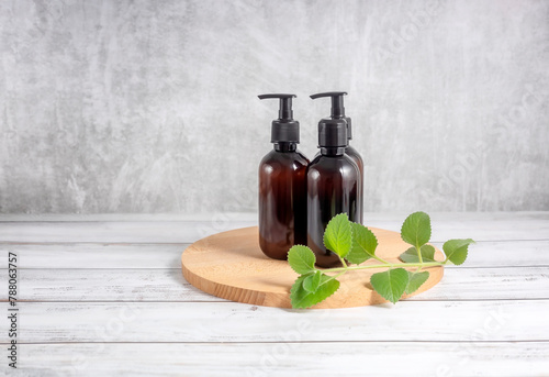 cosmetic bottles on a wooden board and a sprig of mint on a gray background