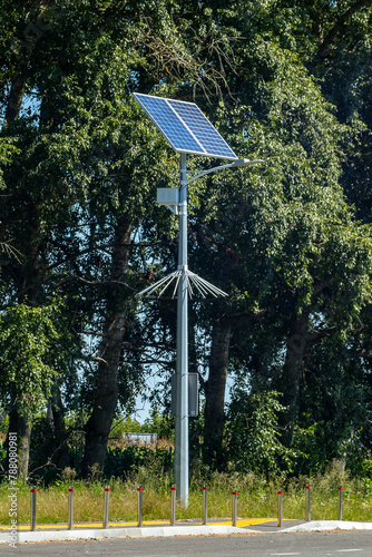 Lamp post with solar panel system on road with blue sky and trees. Autonomous street lighting using solar panels.Alternative renewable energy systems on the street.