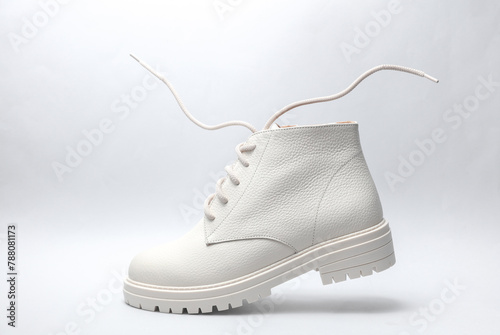 White leather boot with flying laces on a gray background.