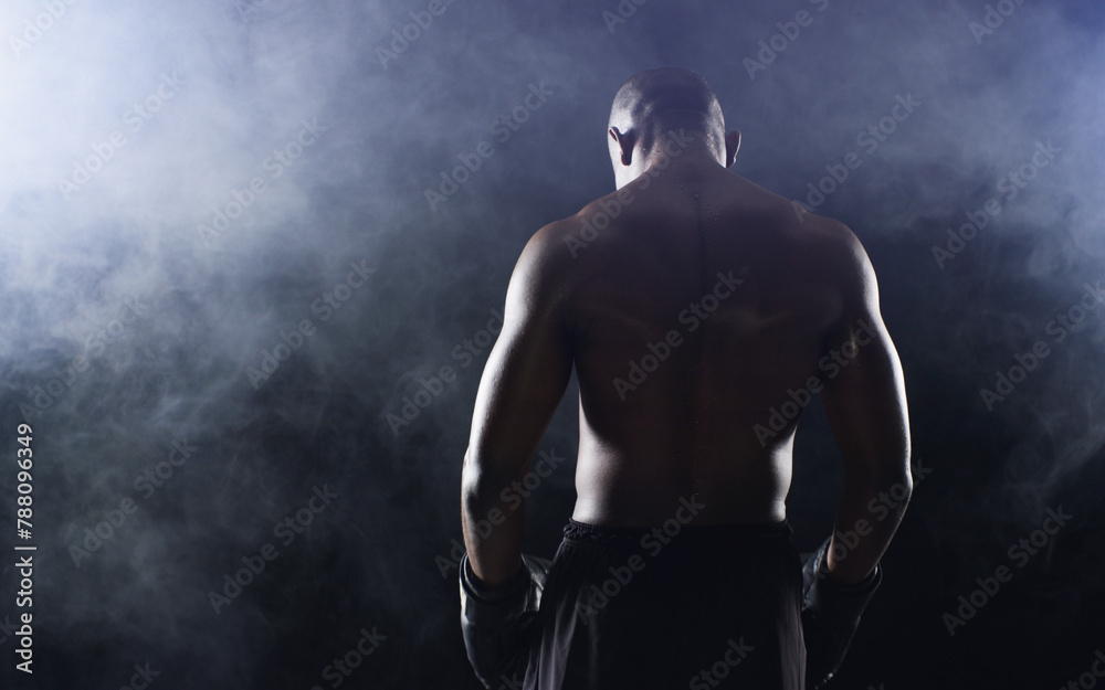 Obraz premium Man, boxer and back of fighter athlete on black background in studio with smoke mist, competition or muscle. Male person, gloves and rear view for sports exercise with endurance, training or serious