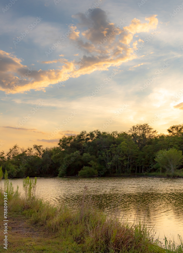 Dramatic sunset clouds reflection along a treelined horizon. Photo taken on Woodlawn Lake in San Antonio Texas