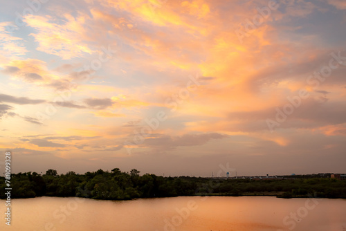 Dramatic sunset clouds reflection along the treelined horizon on Woodlawn Lake San Antonio Texas photo
