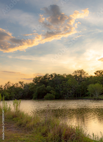 Dramatic sunset clouds reflection along a treelined horizon. Photo taken on Woodlawn Lake in San Antonio Texas