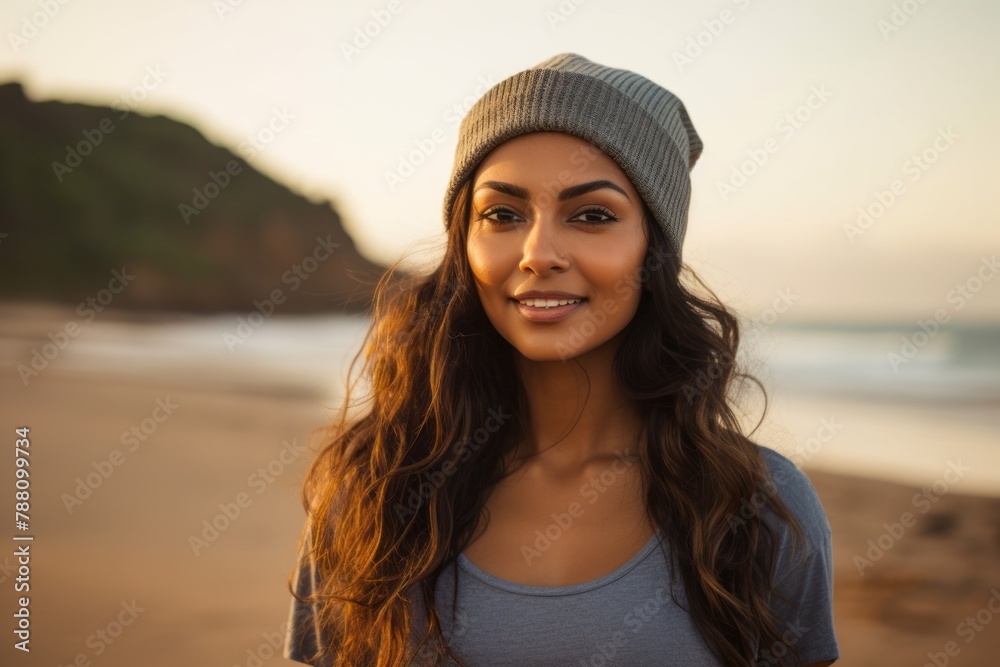Portrait of a content indian woman in her 20s sporting a trendy beanie on sandy beach background Portrait of a content indian woman in her 20s sporting a trendy beanie on sandy beach background