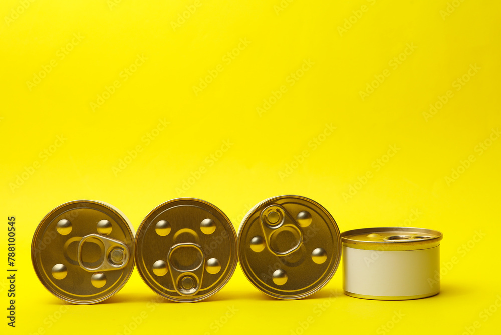 Fototapeta premium Tin cans of canned food with white labels on yellow background, mockup for your design