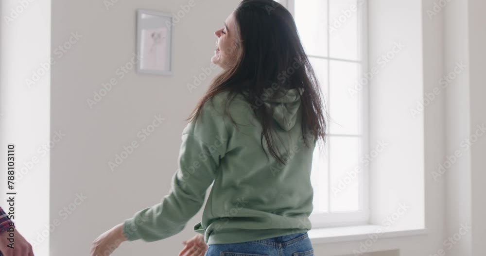 Happy young joyful couple running in new apartment and smiling celebrating moving day looking at the view from window and hugging. Relocating, real estate and mortgage concept. 4k video Happy young joyful couple running in new apartment and smiling celebrating moving day looking at the view from window and hugging. Relocating, real estate and mortgage concept. 4k video