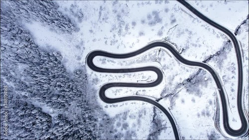 Aerial view of winding mountain road slowly revealing the valley, at Bonaigua Pass in Spain during winter, surrounded by tall trees covered with snow photo