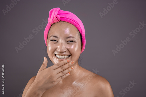 Happy Asian woman enjoying skincare routine.