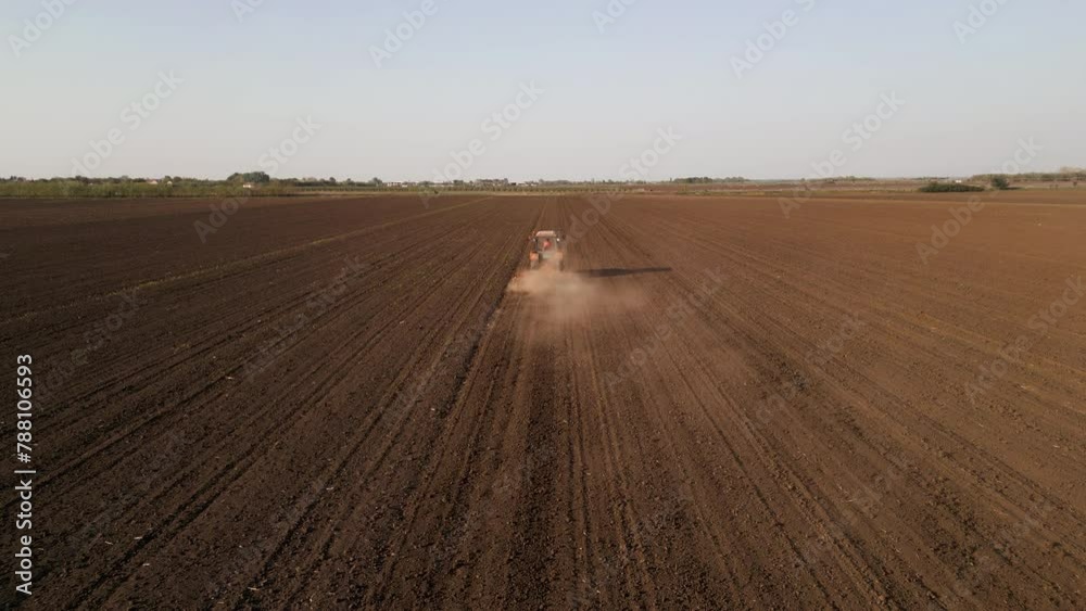 Aerial rear view of tractor harrowing a field at sunset. Aerial rear view of tractor harrowing a field at sunset.