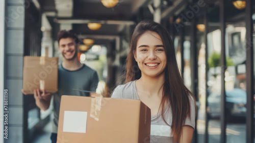 Young happy couple moving to new house holding paper boxes in hands