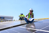Female engineer works installing solar panels on the roof. Engineer or worker working on solar panels or photovoltaic cells on the roof of a business building.