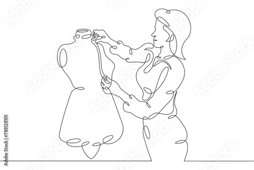 One continuous line.A fashion designer designs a dress. A seamstress works with a mannequin.Fashion designer, dressmaker, seamstress, sewing workshop or courses, tailoring concept. Continuous line dra