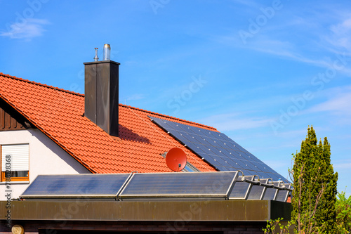 Solarthermieanlage auf Garagendach vor rotem Hausdach mit Photovoltaikanlage  photo