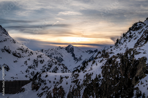 Athletes doing backcountry ski with a landscape of snowy mountains on a sunny day. Sunset over the snowy mountains.
