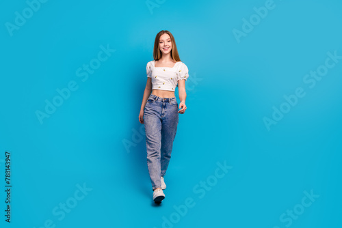 Full length portrait of lovely girl walk empty space wear top isolated on blue color background
