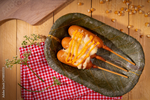 american food with recycle biodegradable leaf plate. fried dough stuffed hot dog called corn dog ad with mayonnaise and cheese sauce serve on disposable dish for environmental friendly save planet